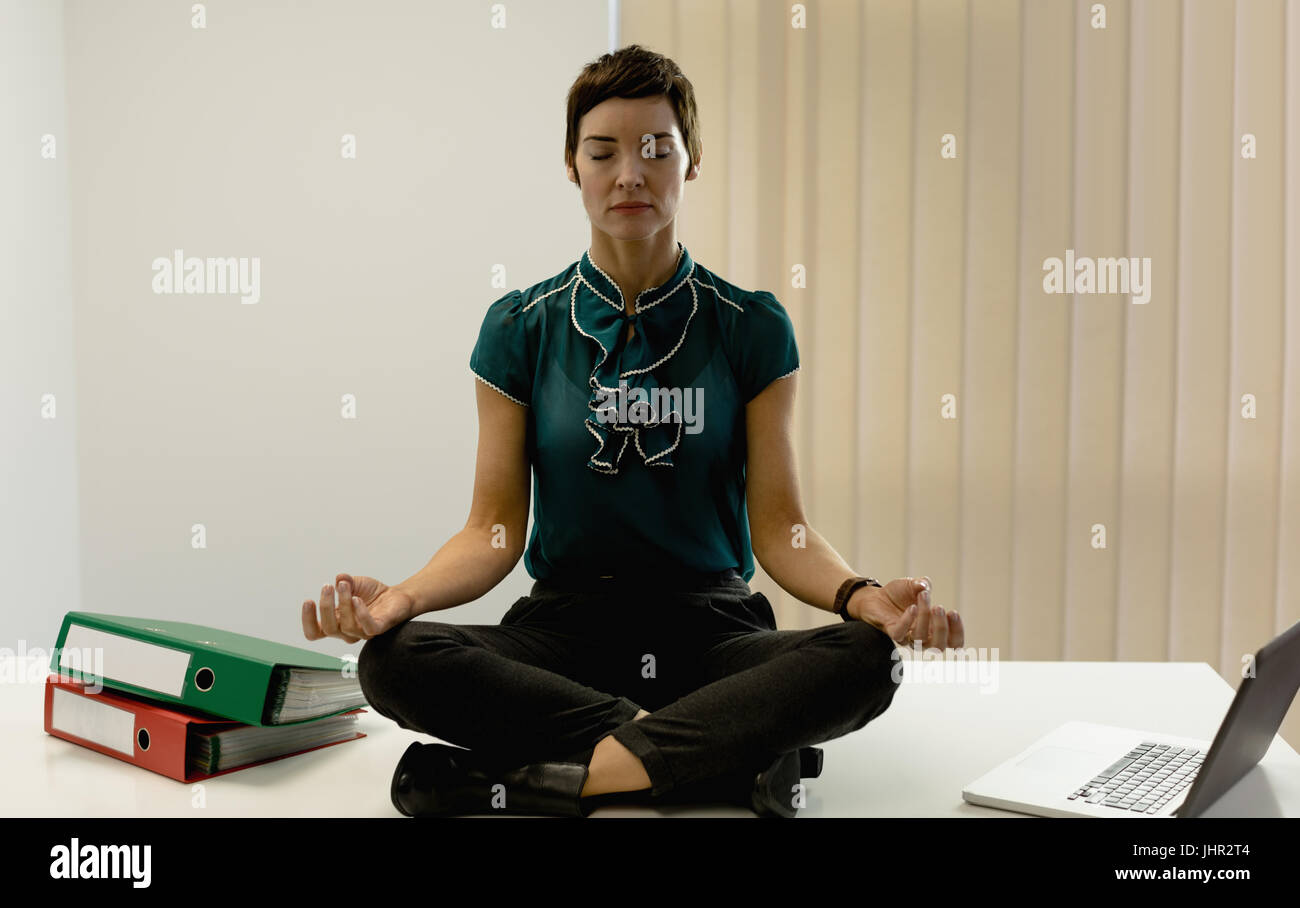 Beautiful businesswoman practicing yoga in office Stock Photo - Alamy