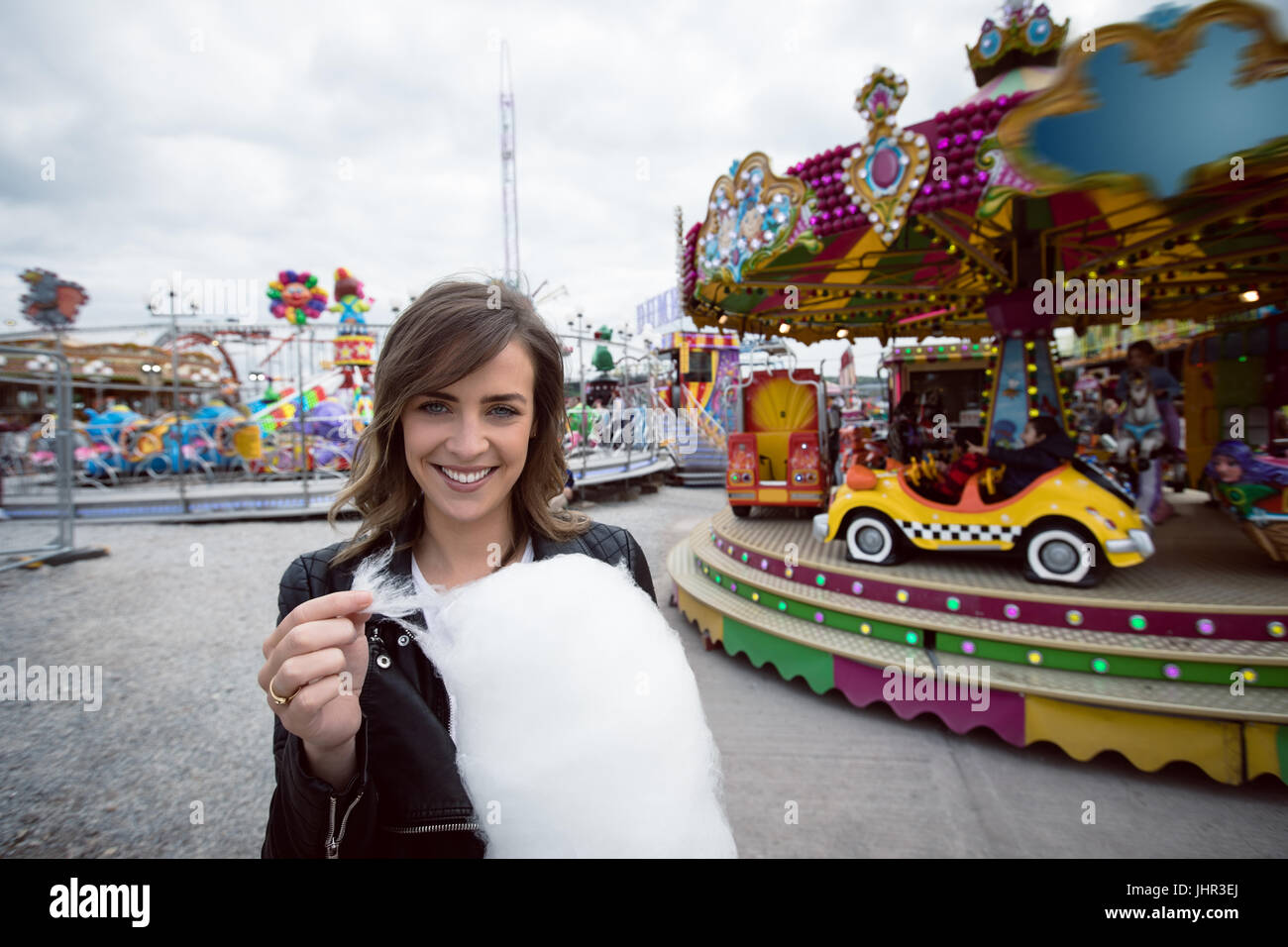 Beautiful woman holding cotton candy in amusement park Stock Photo - Alamy