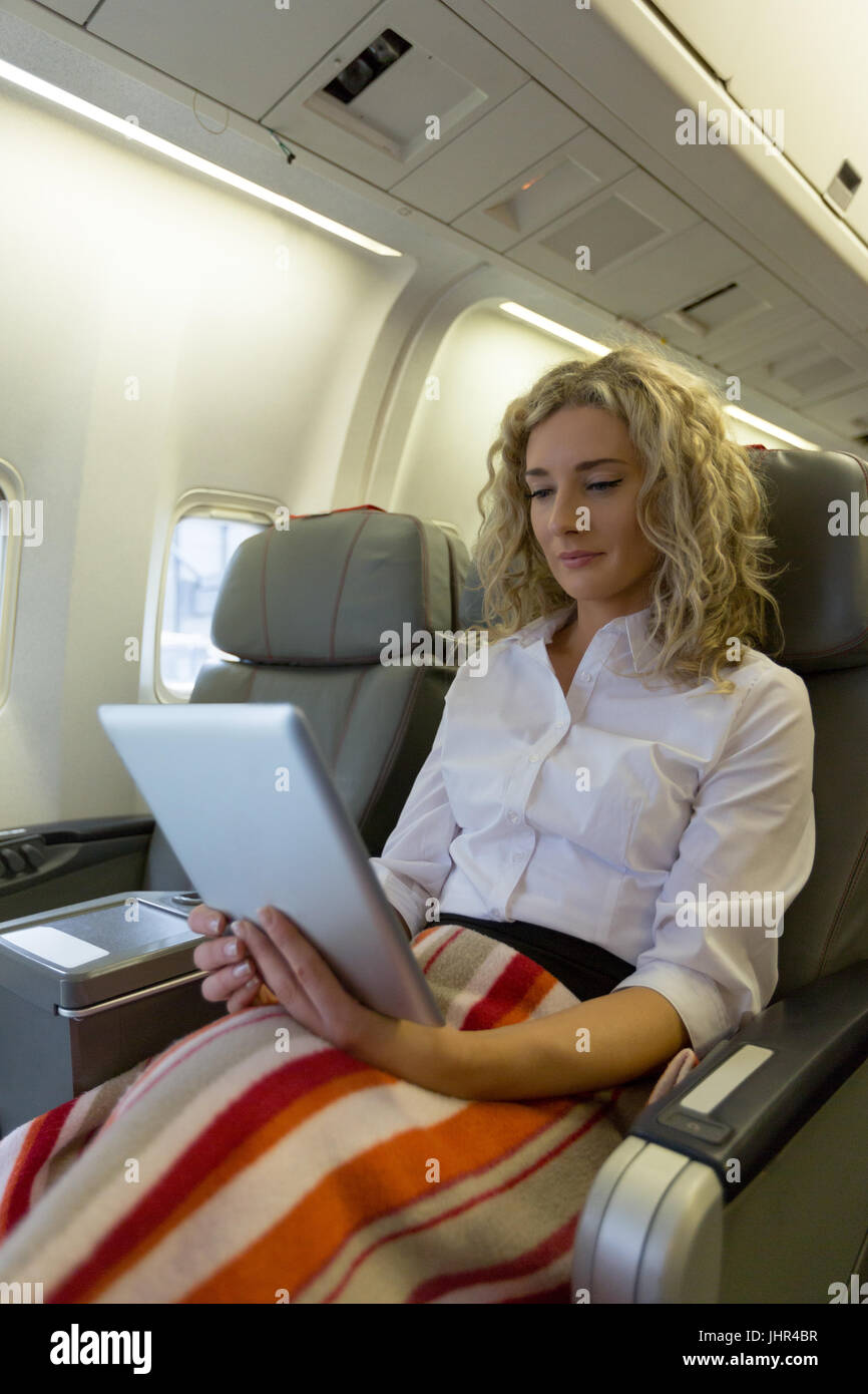 Beautiful woman using digital tablet while sitting in an aircraft seat Stock Photo