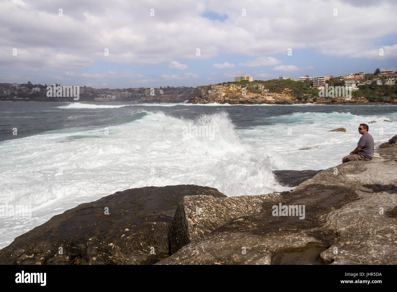 Man sat watching the rough seas off the Sydney coast, New South Wales, Australia Stock Photo