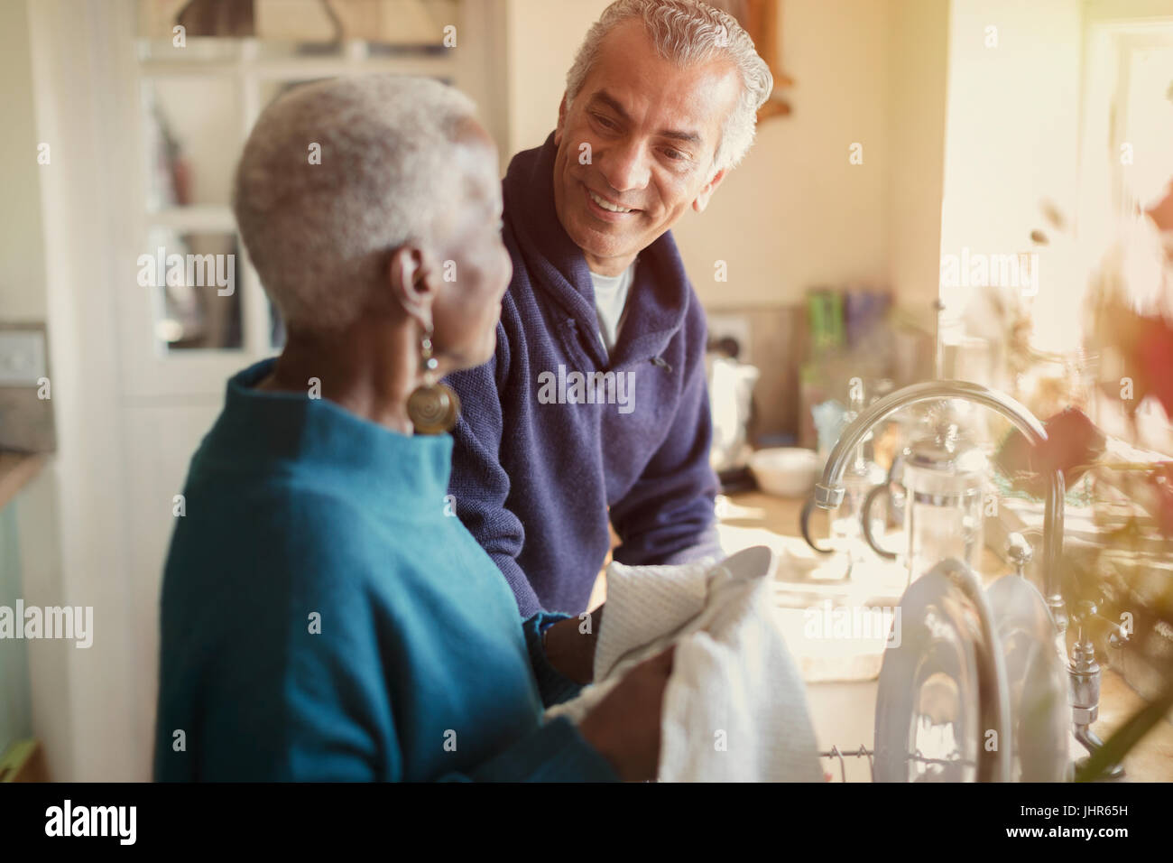 Senior couple talking and doing dishes in kitchen Stock Photo