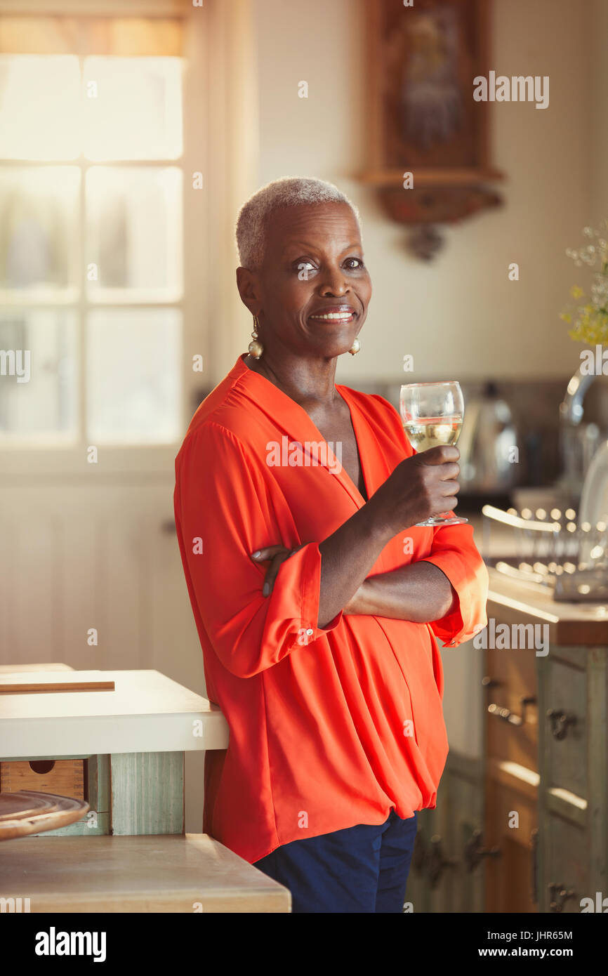 Portrait smiling senior woman drinking wine in kitchen Stock Photo