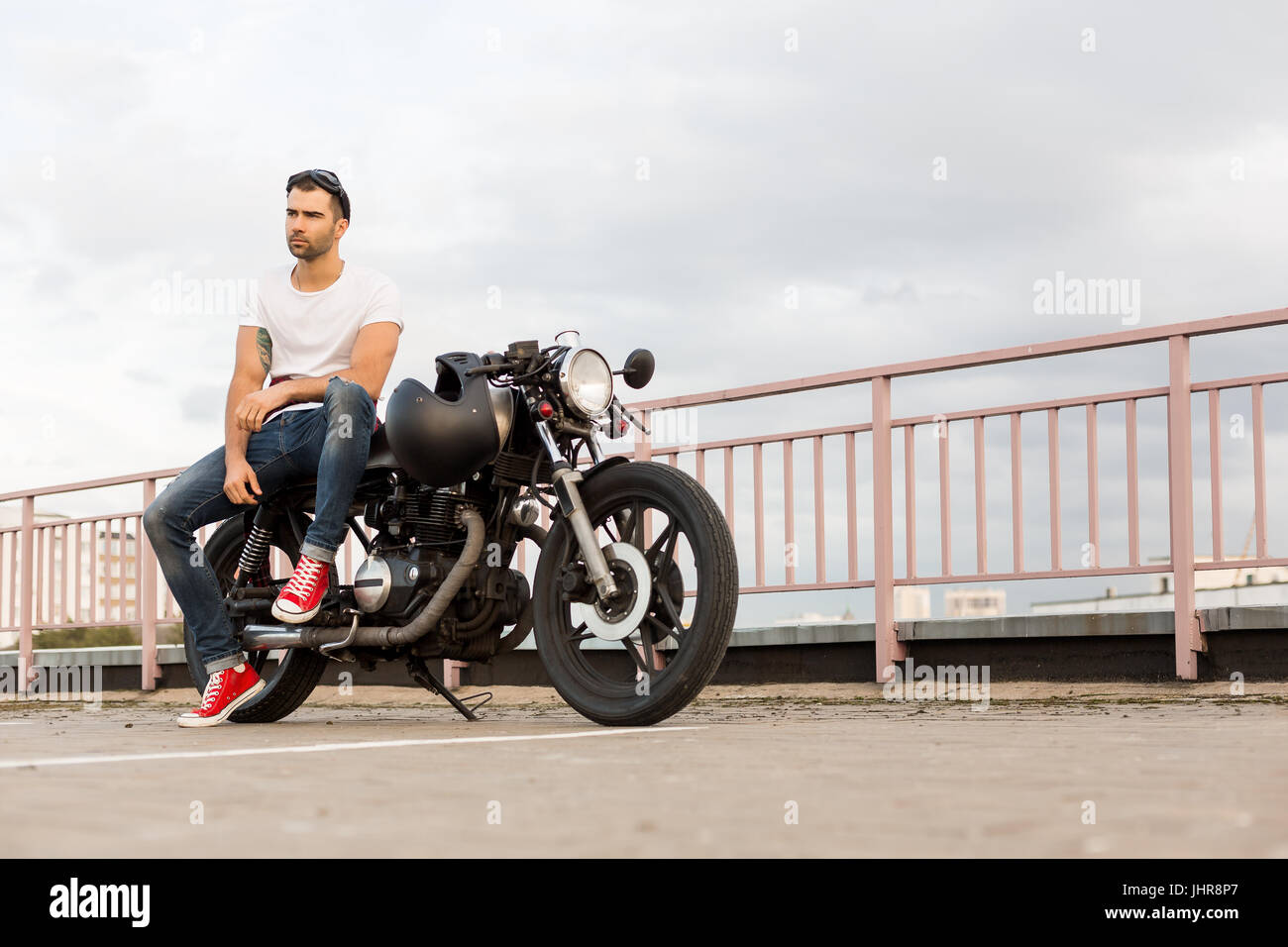 Rider guy with beard and mustache in red sneakers sit on classic style ...