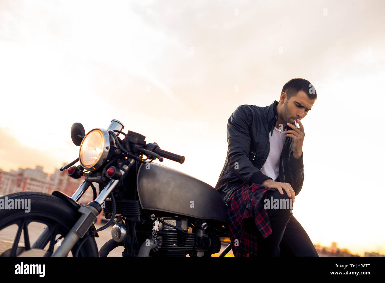 Handsome rider man with beard and mustache in biker jacket smoking
