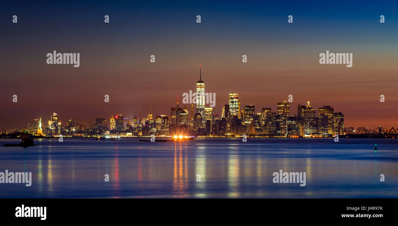 First light of the day on Lower Manhattan skyscrapers from New York City Harbor. Financial District and Midtown West Stock Photo