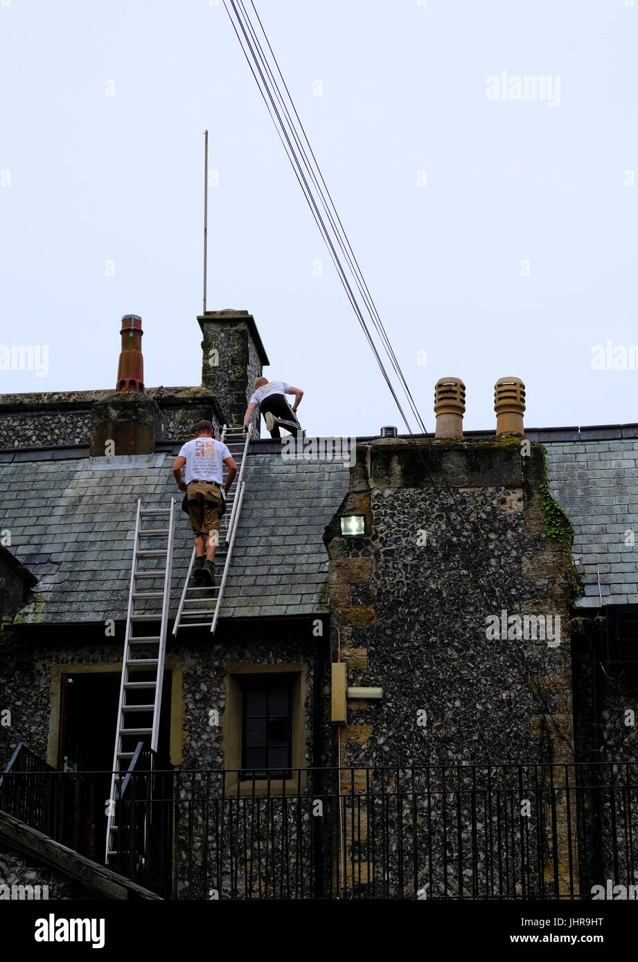 Two male roofers carrying out maintenance work on roof of listed building. Highdown Towers, Worthing, West Sussex, UK Stock Photo