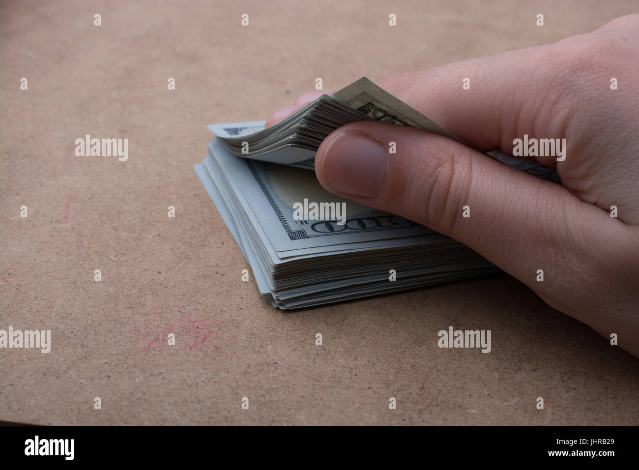 Hand holding banknote bundle of US dollar on a linen canvas background ...