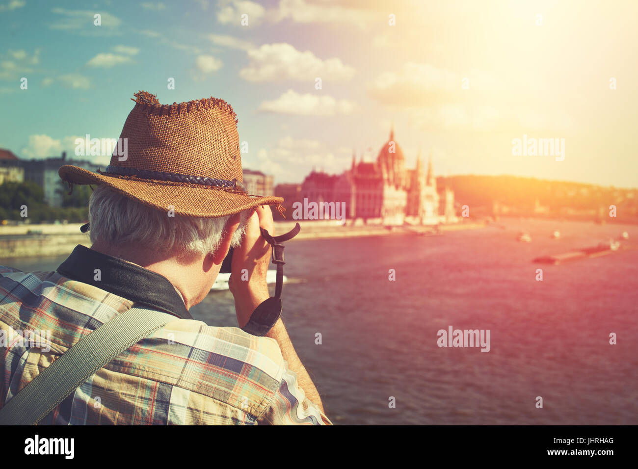 Pensioner tourist in hat capturing Hungarian Parliament building at Budapest in vintage style Stock Photo