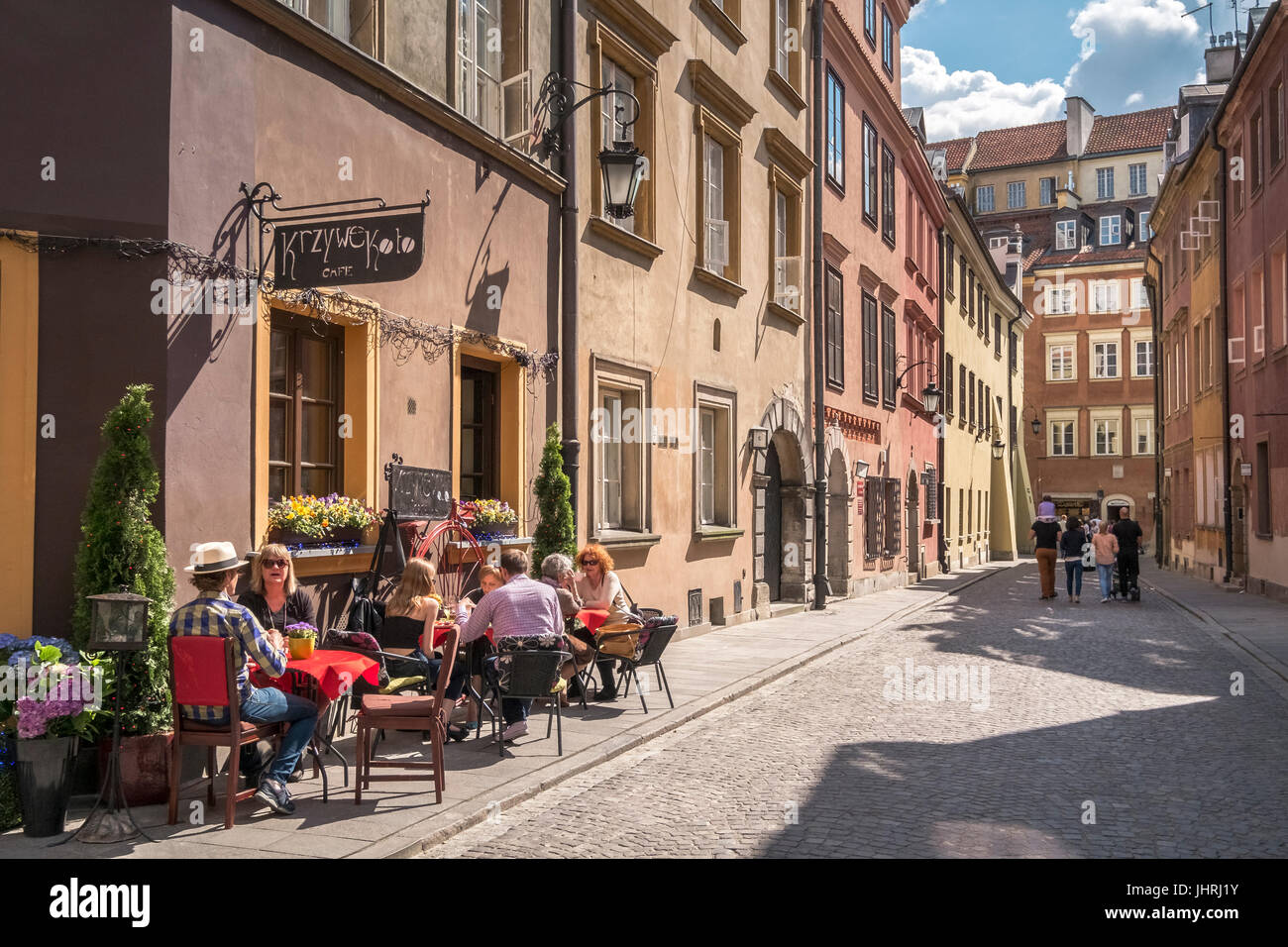 Tourists sitting in sunshine outside Krzywe Kolo Cafe, Old Town, Warsaw, Poland Stock Photo