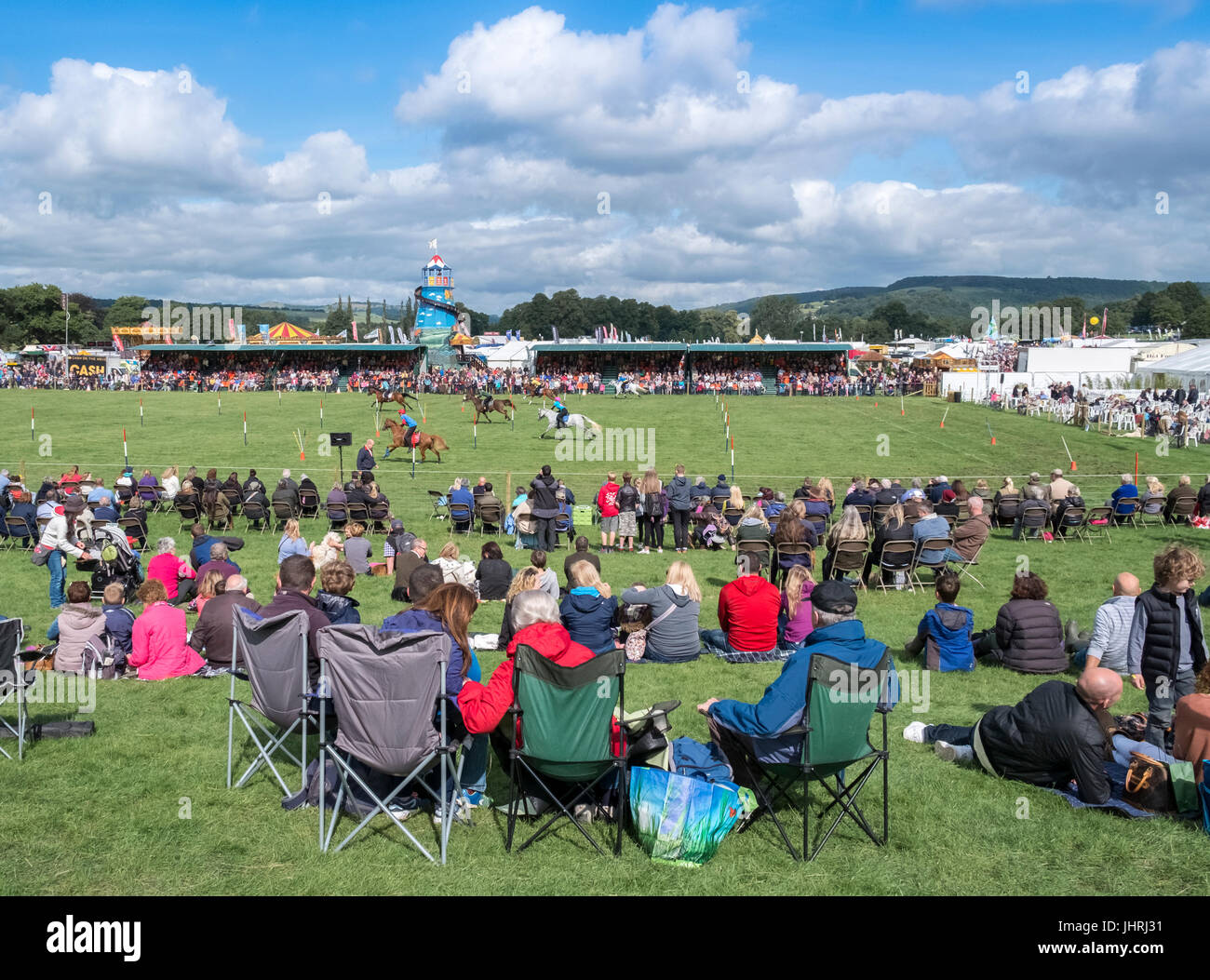 Spectators at an English Country Fair event watch horse race performers