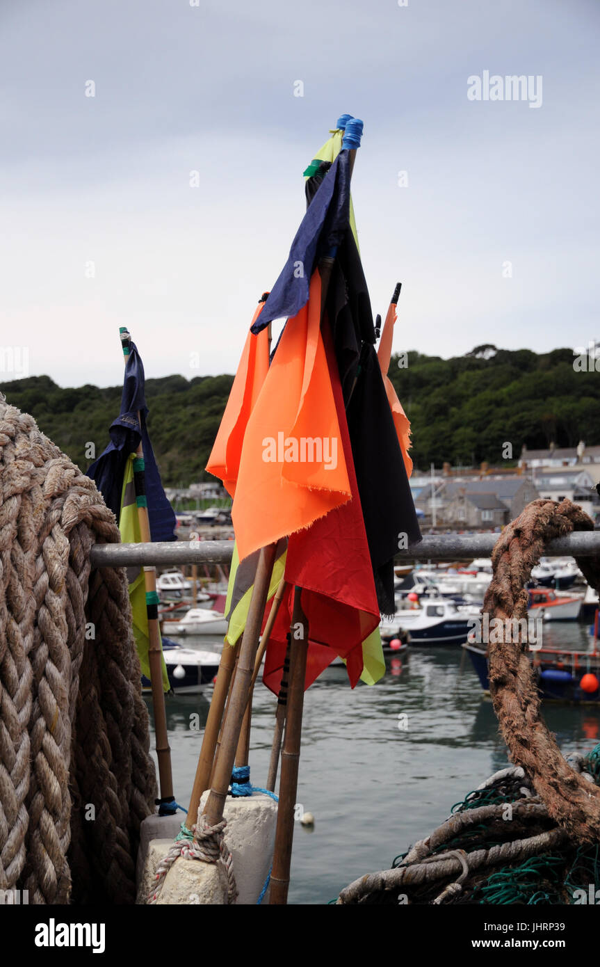 Marker flags from crab and lobster pots on the quayside at Lyme Regis harbour in Dorset. A number of boats fish inshore waters from the port. Stock Photo