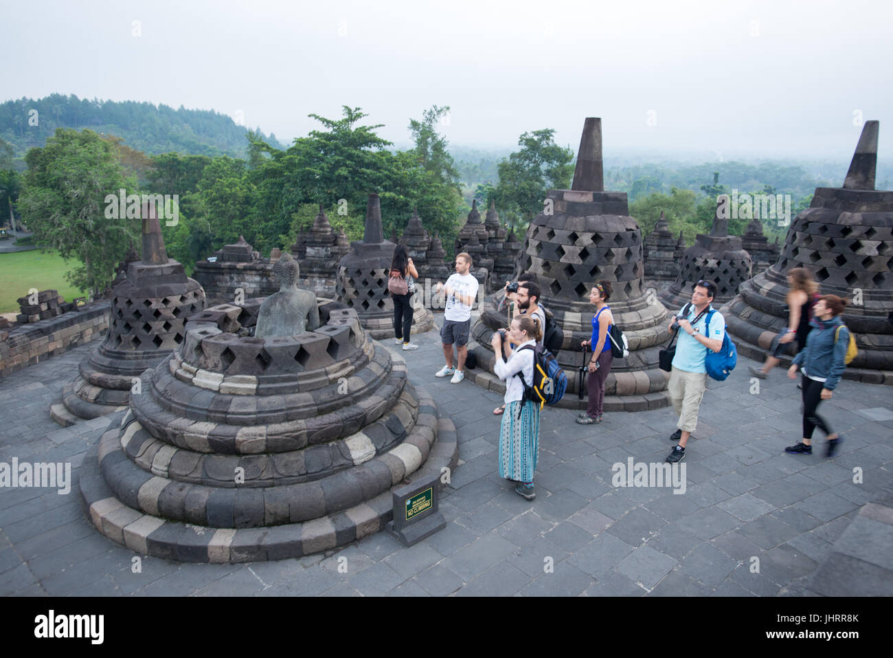 Tourists are taking picture of invincible Buddha statue in an open stupa, Borobudur Temple Java Indonesia. Stock Photo