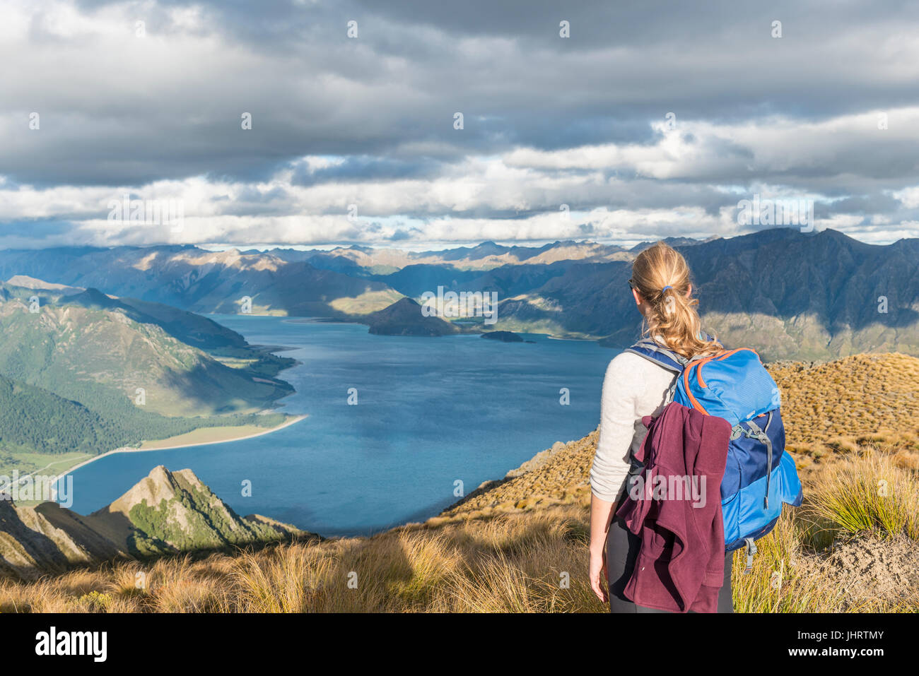 Female hiker looking at lake, Lake Hawea and mountain landscape, Isthmus Peak, Otago, South Island, New Zealand Stock Photo