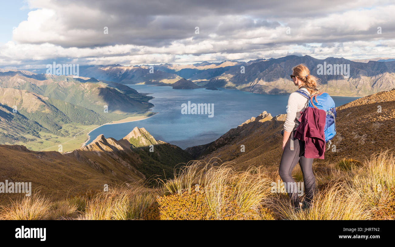 Female hiker looking at lake, Lake Hawea and mountain landscape, Isthmus Peak, Otago, South Island, New Zealand Stock Photo