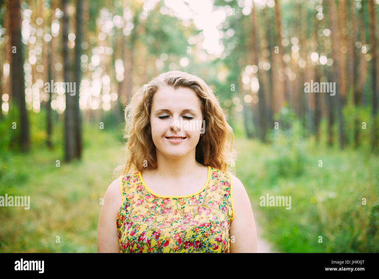 Portrait Of Young Pretty Plus Size Caucasian Happy Girl Woman With Closed Eyes, Wavy Brown Long Hair In Summer Forest Background. Stock Photo