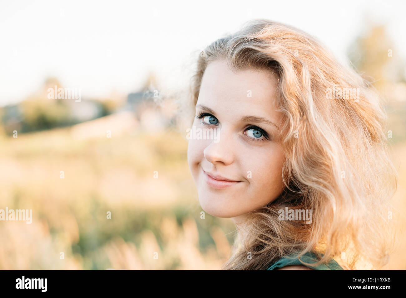 Portrait Of Young Pretty Plus Size Caucasian Happy Girl Woman With Blue Eyes, Wavy Brown Long Hair In Summer Meadow Background. Stock Photo