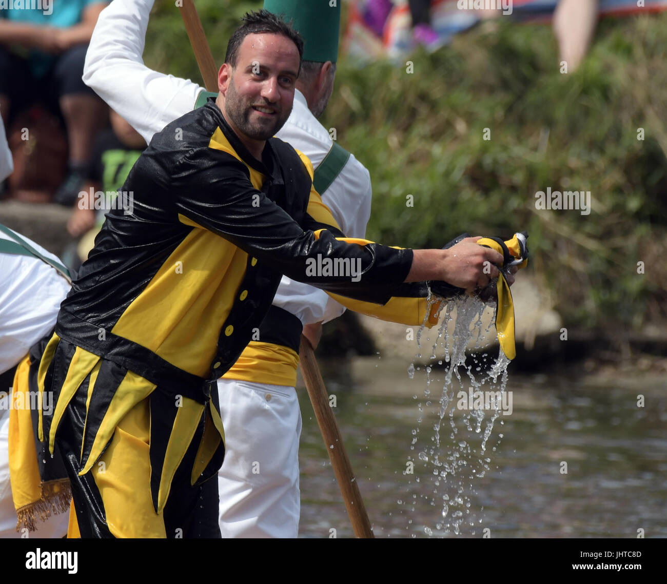 Ulm, Germany. 16th July, 2017. The jester dressed on yellow and black wrings out his soaking hat after crashing into the waters of the Danube river in Ulm, Germany, 16 July 2017. Every four years the water jousting festival takes place in Ulm - costumed participants try their best to tip each other into the Danube river with lances. Photo: Stefan Puchner/dpa/Alamy Live News Stock Photo