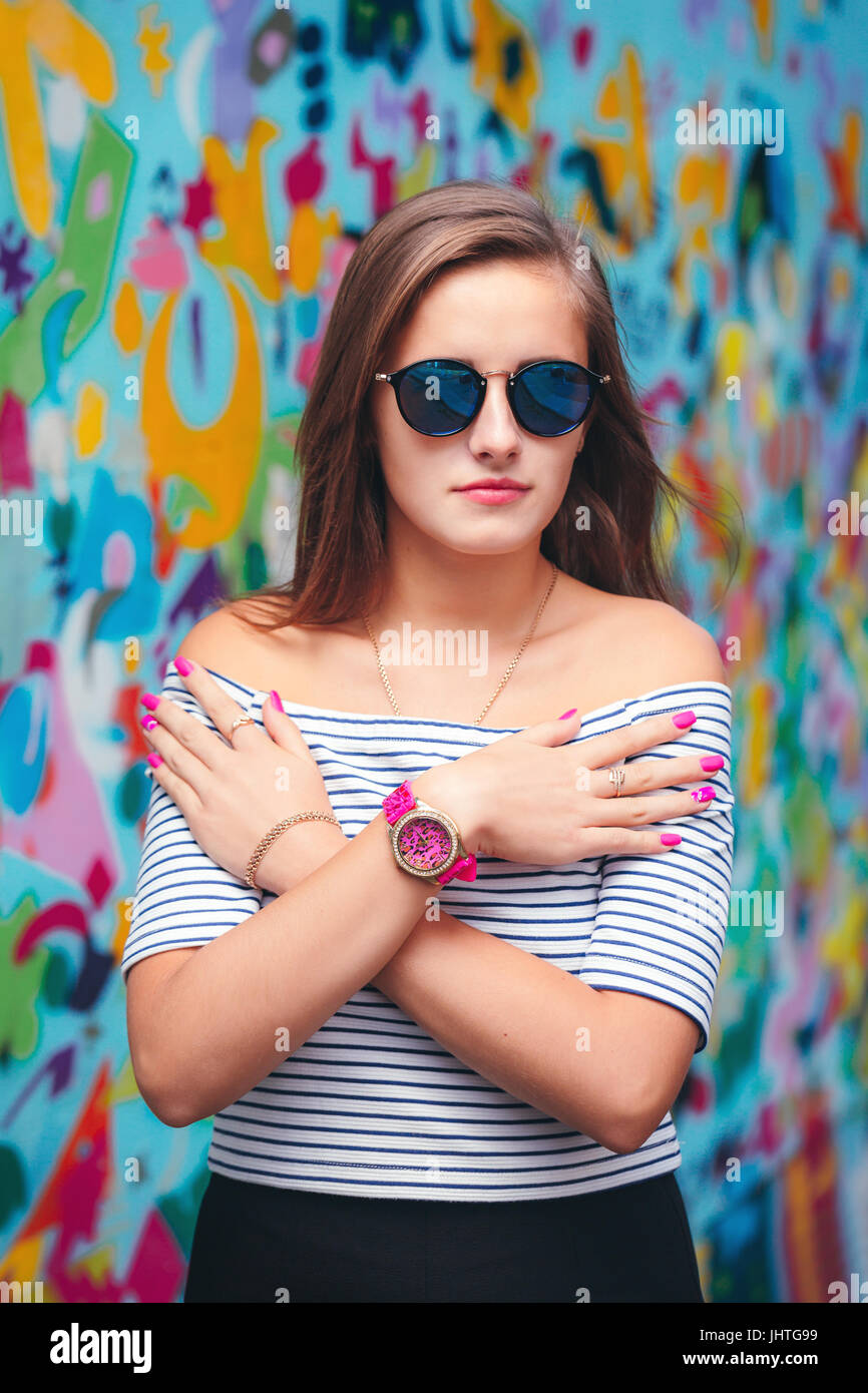 cheerful young woman with round glasses posing on the background of bright walls Stock Photo