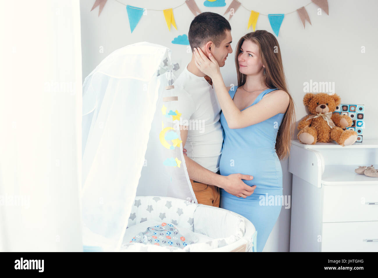 Happy young expecting couple in love standing near a new baby crib Stock Photo