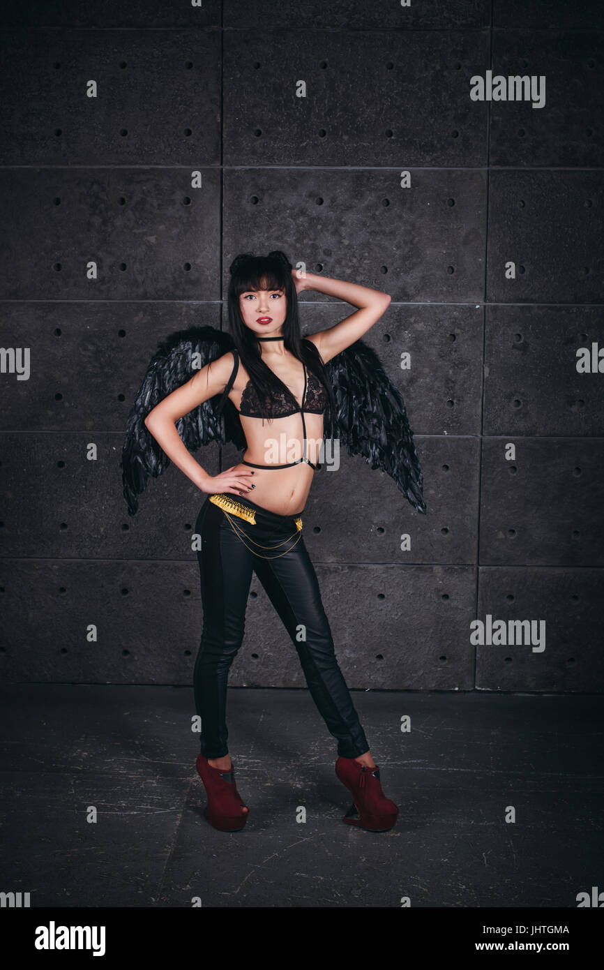 Black Angel. Beautiful model woman in underwear thin leather jacket and trousers, wings, posing in stduio. Stock Photo