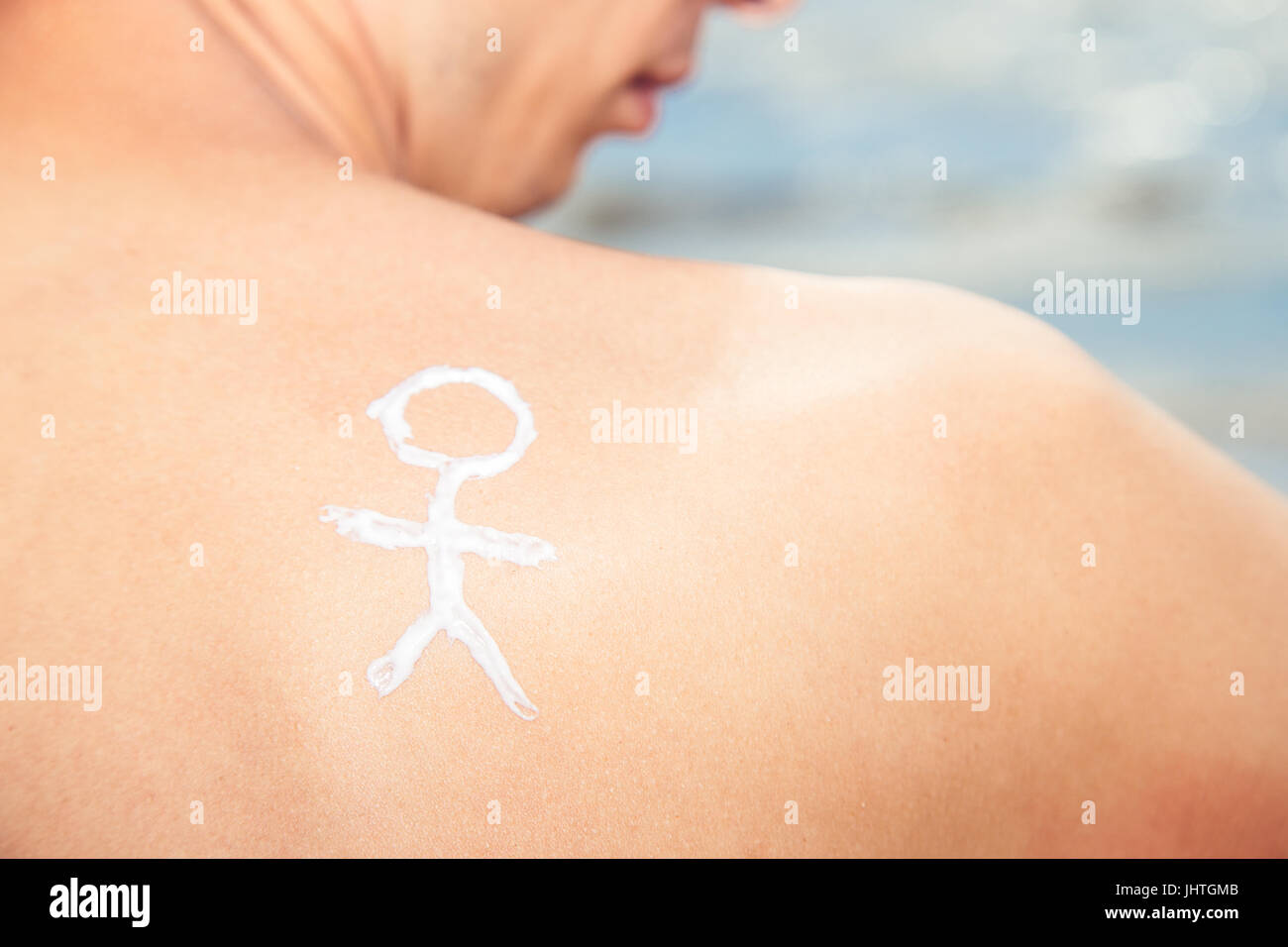 Lotion man with sunscreen with a little man on the sea background Stock Photo