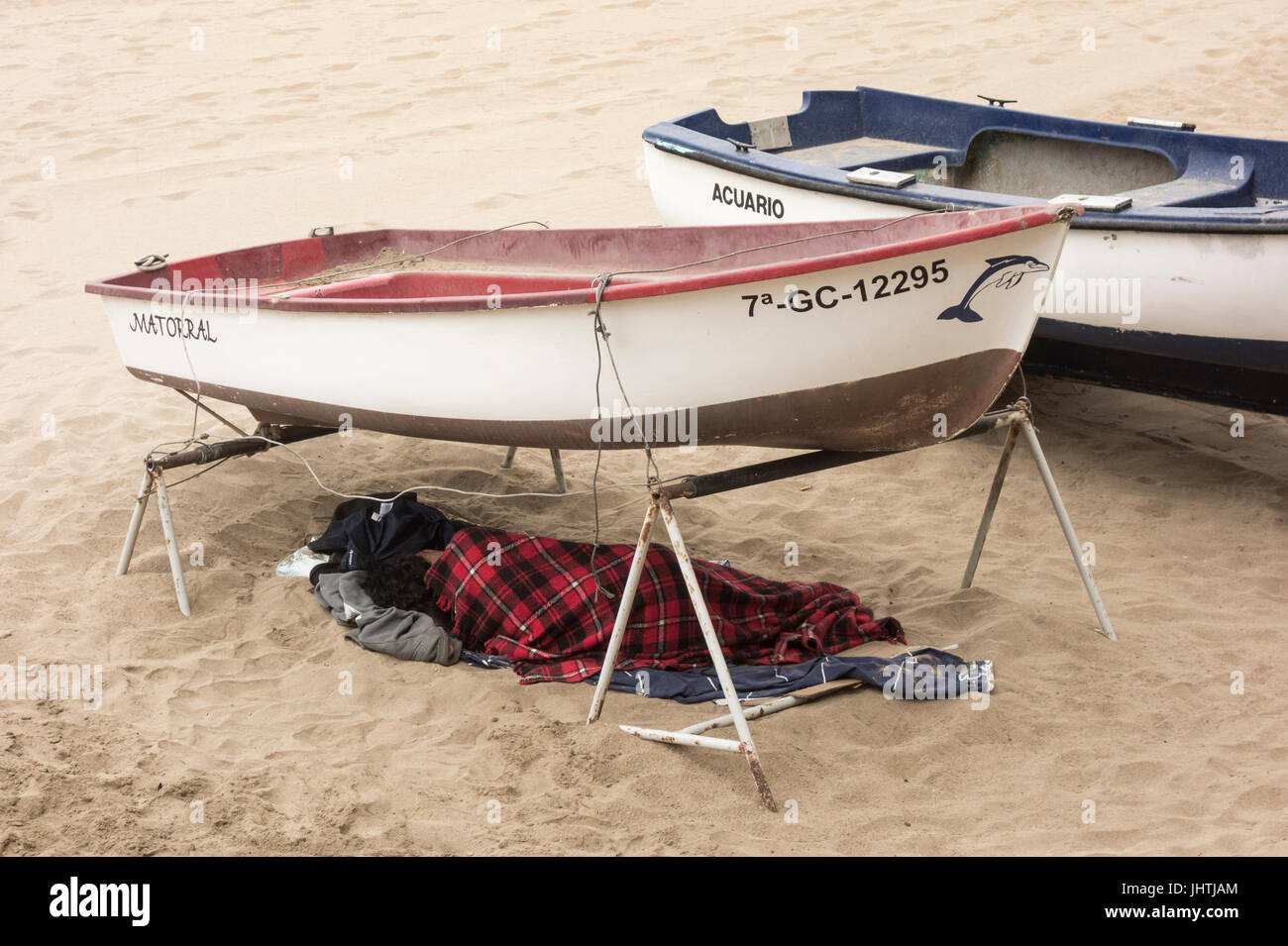 Homless Man On Raft Homeless person sleeping under boat on beach in Spain Stock Photo - Alamy