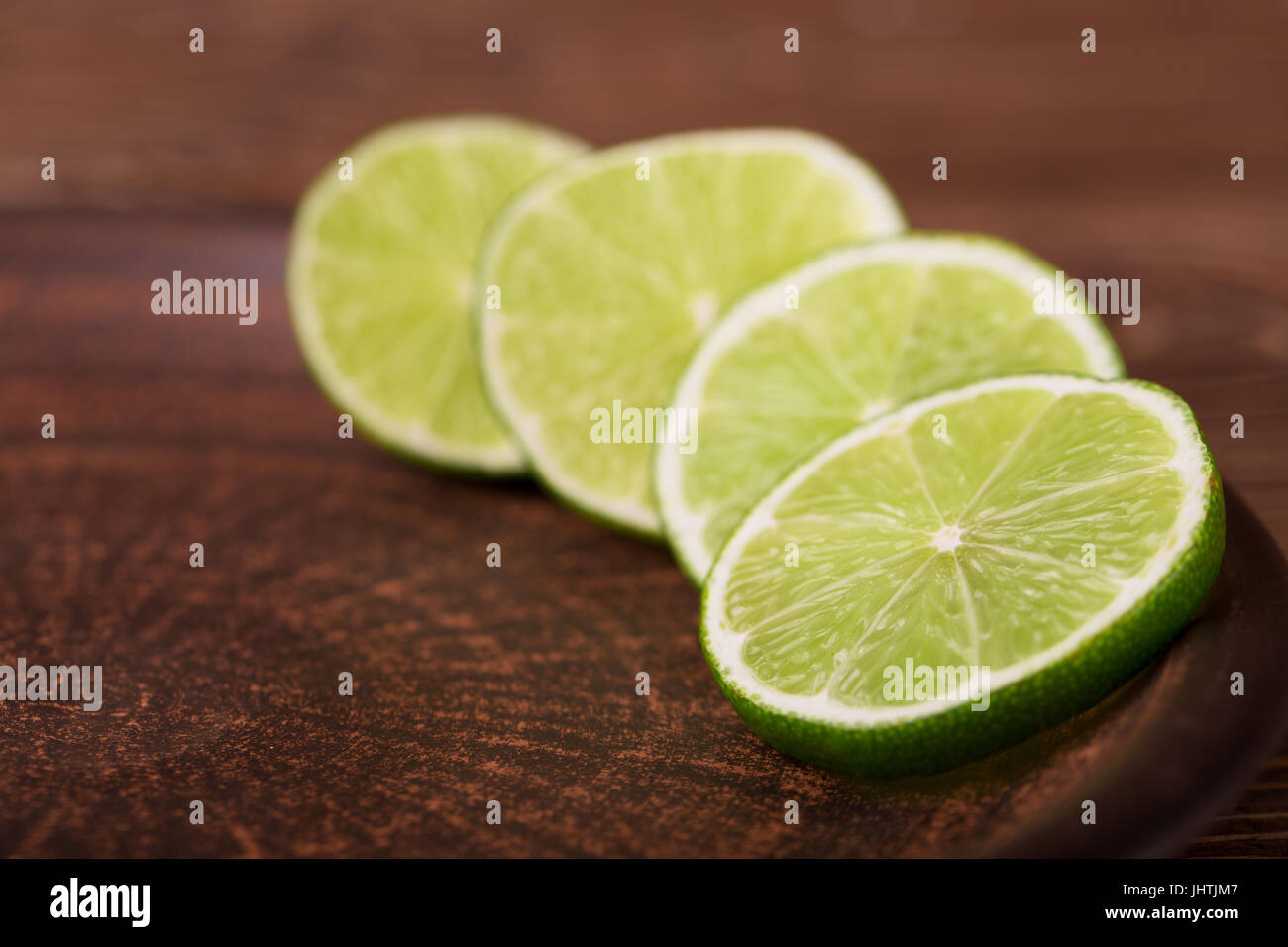 Lime slices on a dark plate on the wooden background Stock Photo