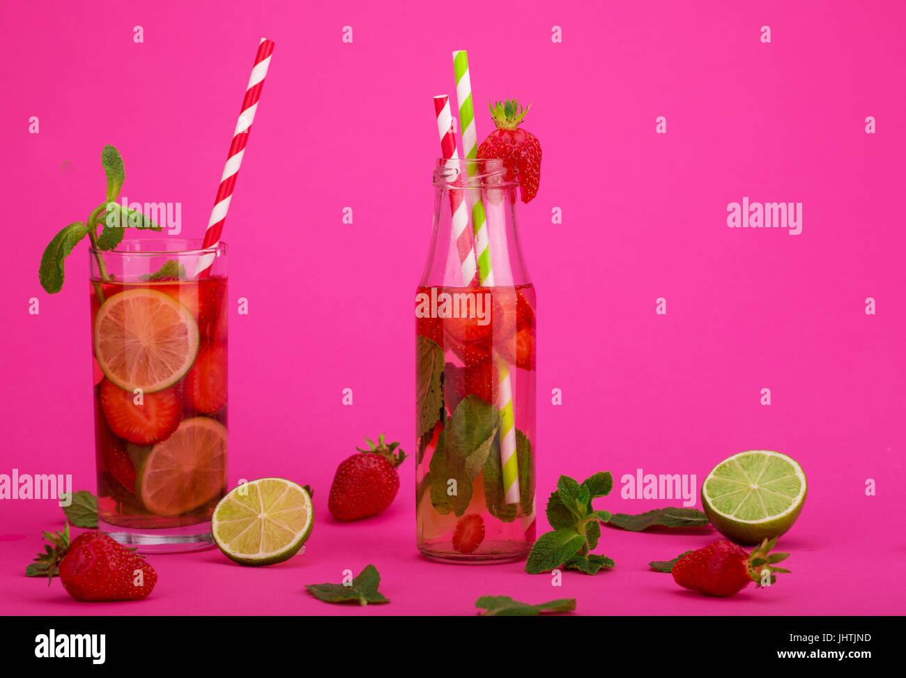 Fresh lemonade with strawberries, lime and mint in a tall glass on a white and pink background Stock Photo