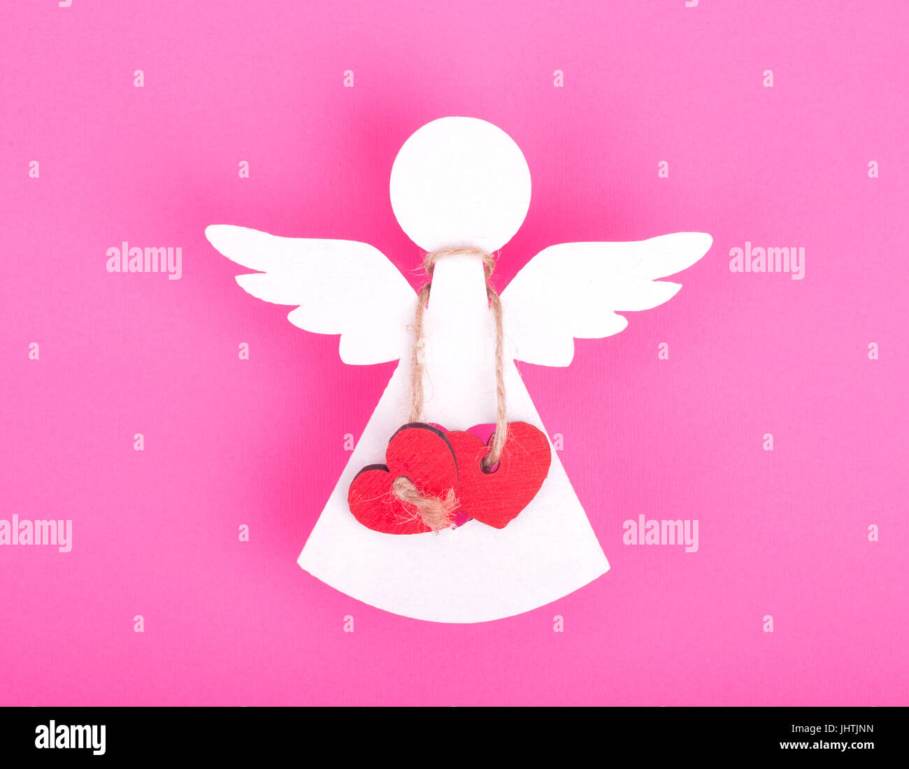 Christmas decorations of white angel two linked red hearts on a pink background Stock Photo