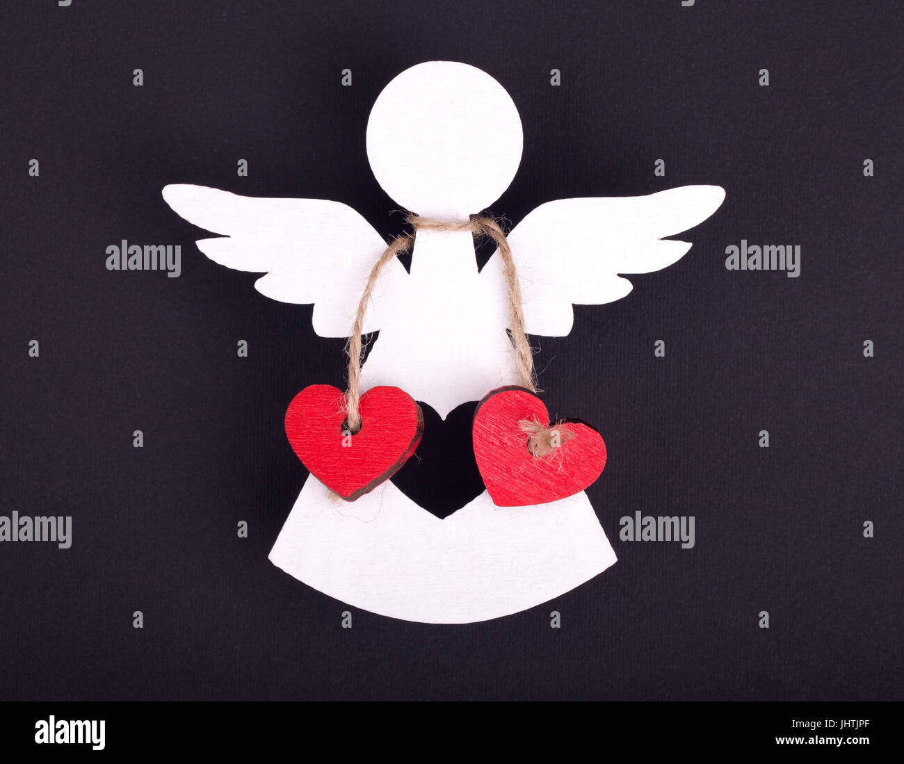 Christmas decorations of white angel with two linked red hearts on a black background Stock Photo