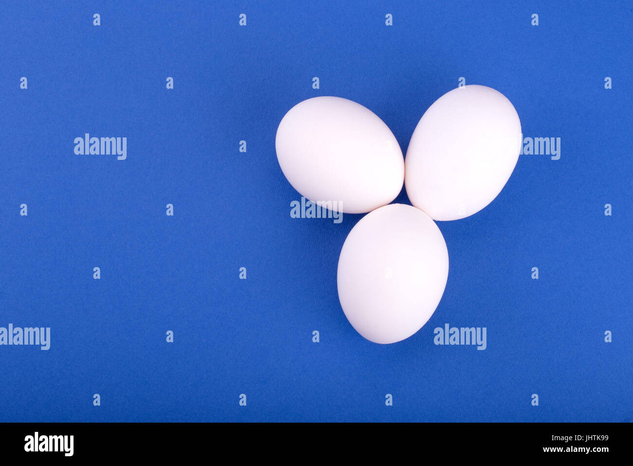 three white eggs on a blue background Stock Photo