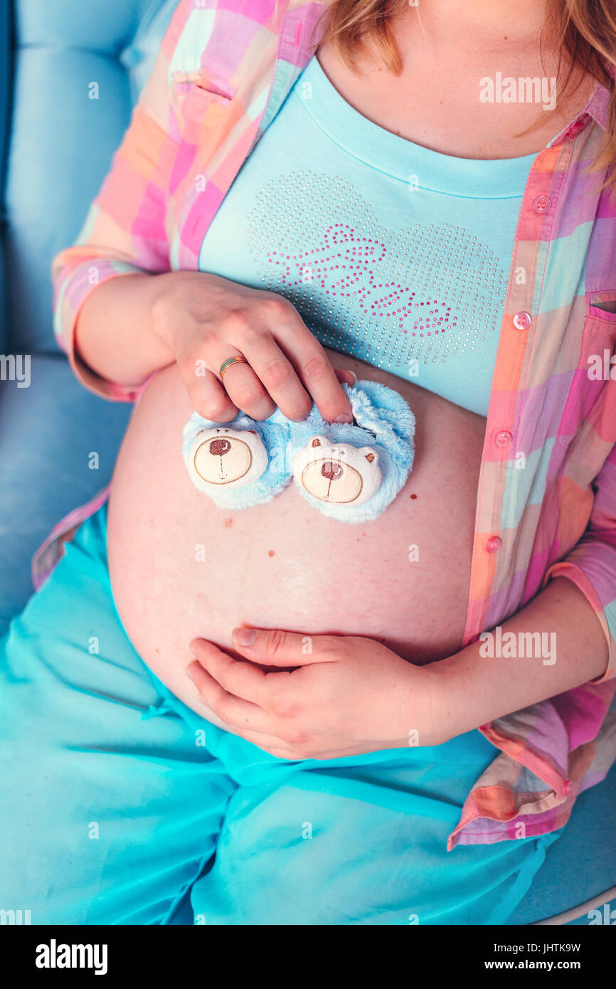 Pregnant woman belly holding baby booties Stock Photo
