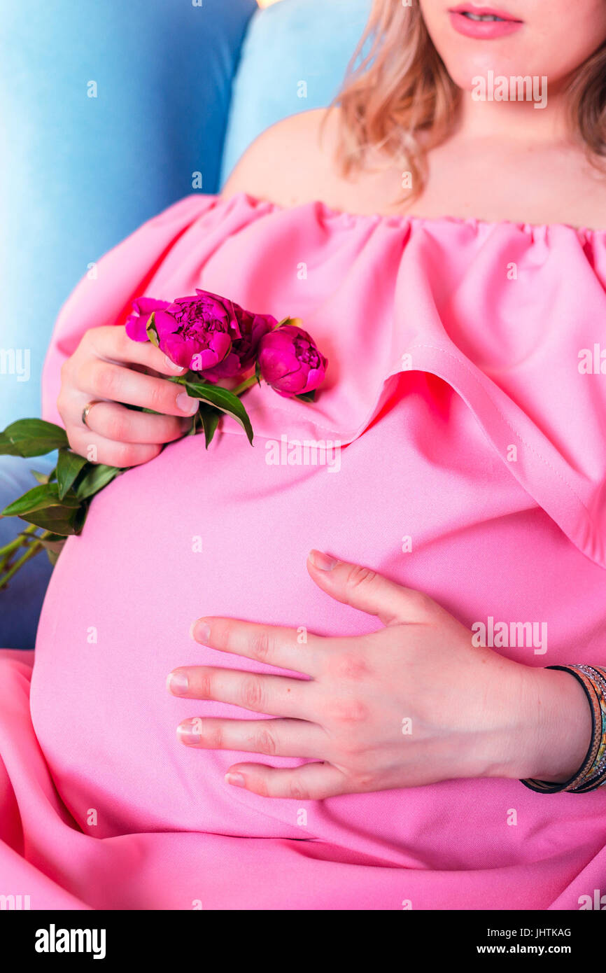 Woman expecting a baby in pink dress in studio Stock Photo