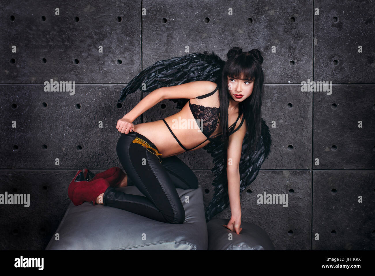 Black Angel. Beautiful model woman in underwear thin leather jacket and trousers, wings, posing in stduio. Stock Photo