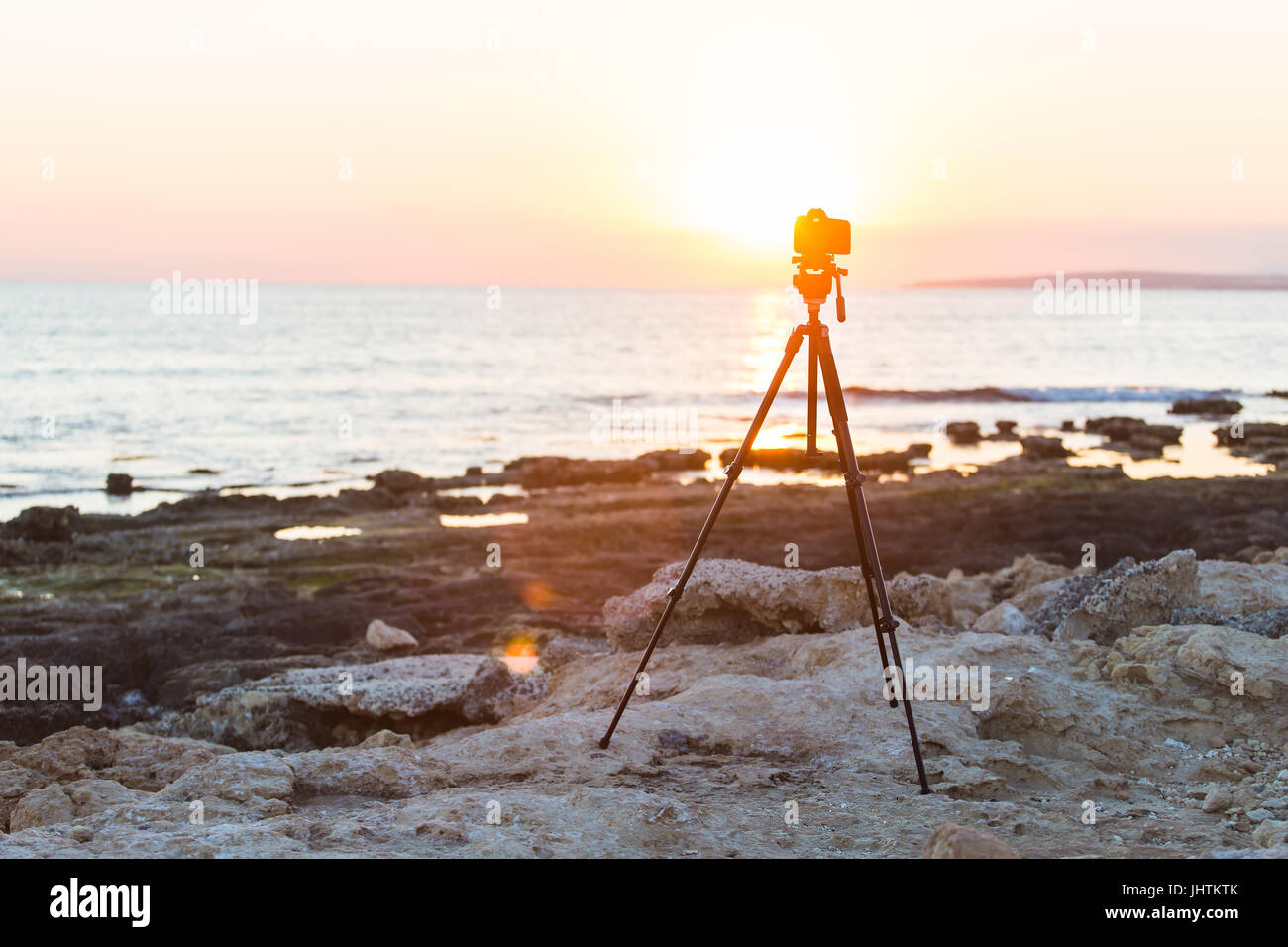 Camera with tripod over sun rising near the beach Stock Photo - Alamy