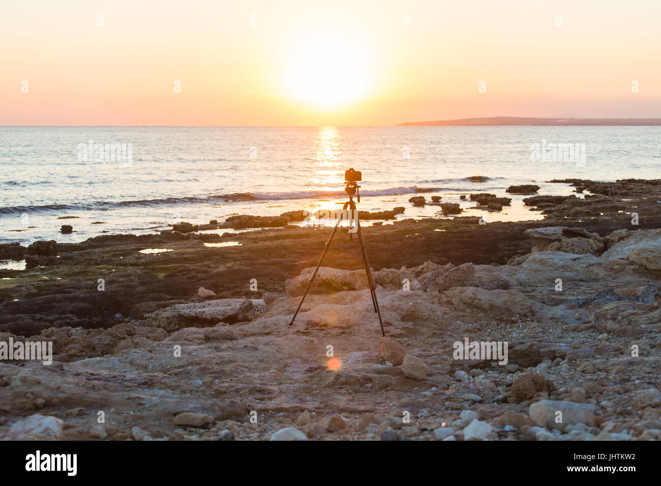 Camera with tripod over sun rising near the beach Stock Photo - Alamy