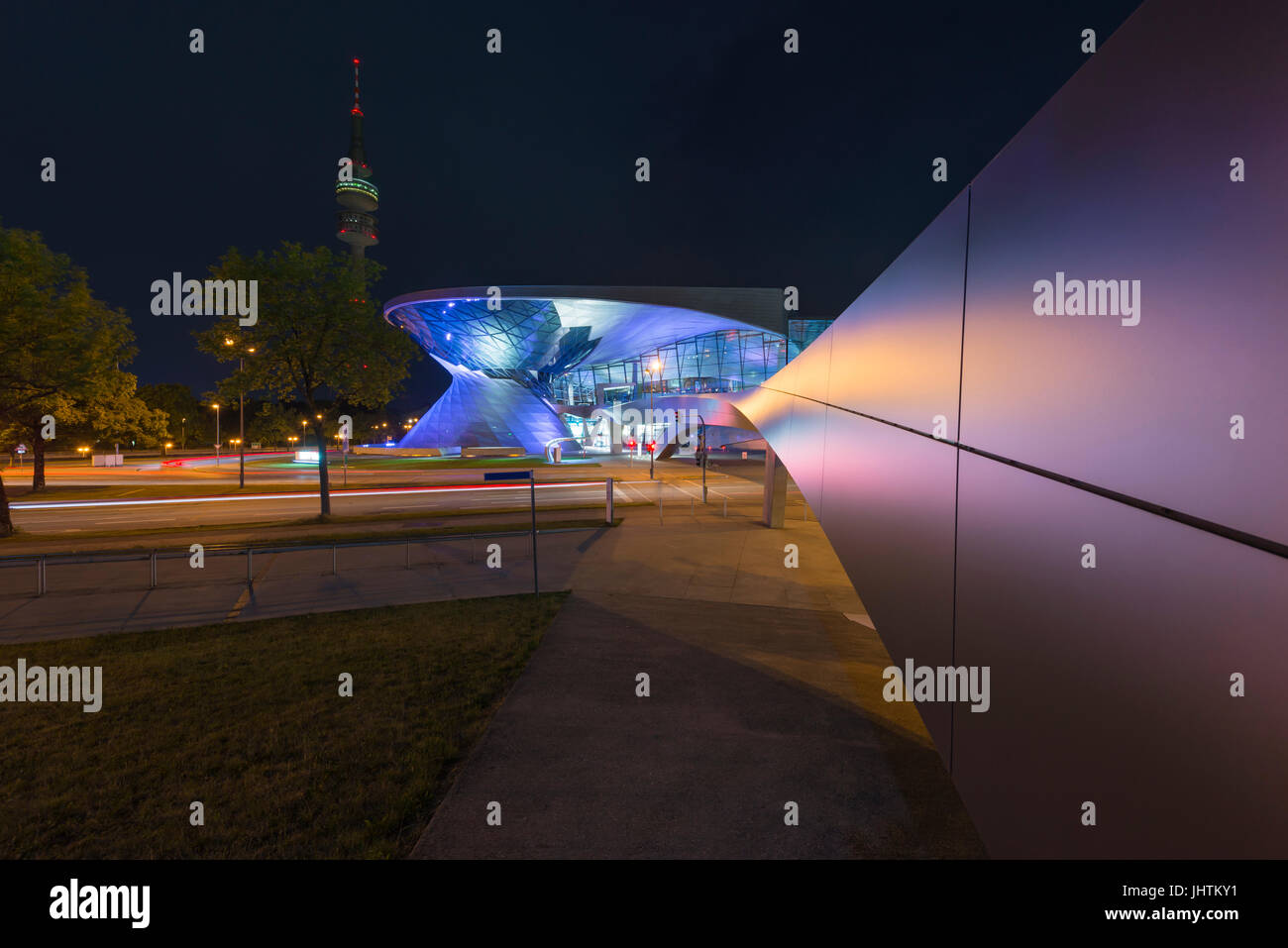 Futuristic architecture of a walkway towards the illuminated facade of the BMW Welt in Munich at night Stock Photo