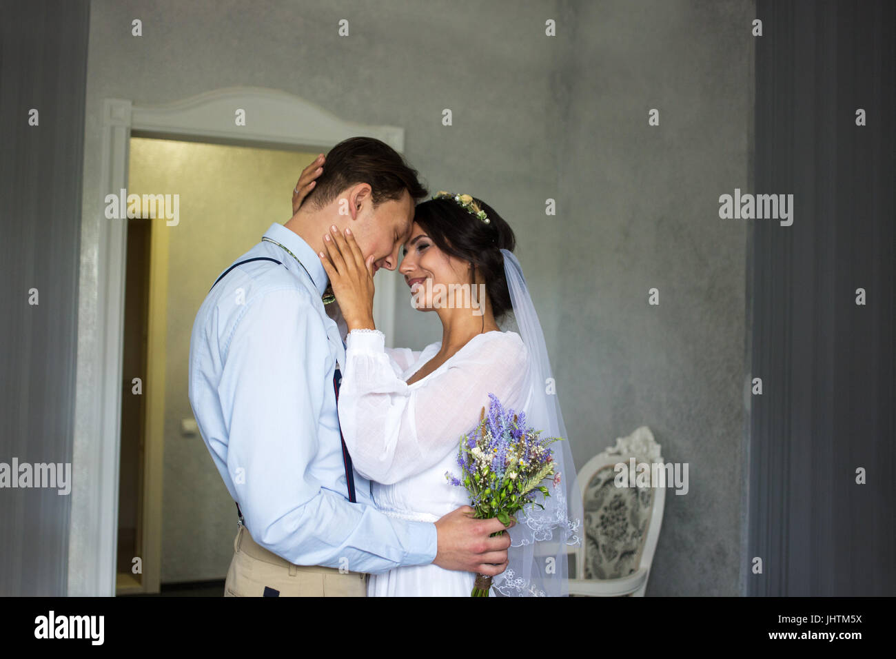 Meeting the bride and groom in the bedroom, the newlyweds are happy. Man with flowers in his hand. Love. Embrace. Stock Photo