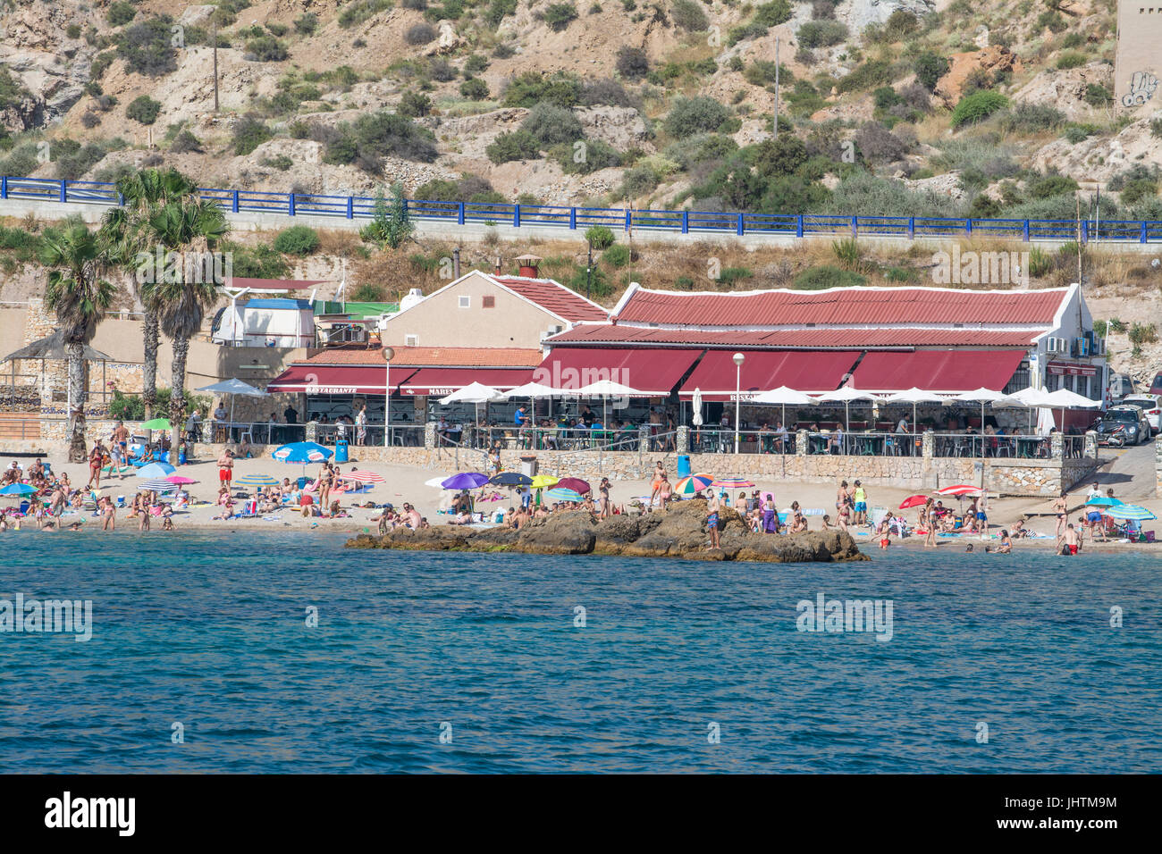 Sunbathers on the beach in front of the restaurant at Cala Cortina near Cartagena in Murcia Spain Stock Photo