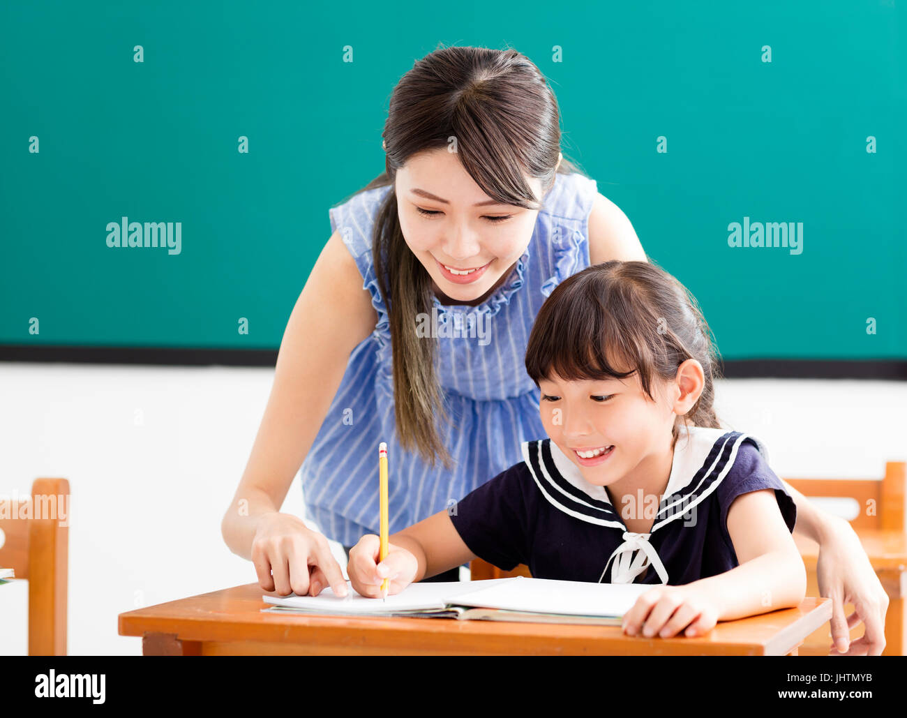 young Teacher helping child with writing lesson Stock Photo - Alamy