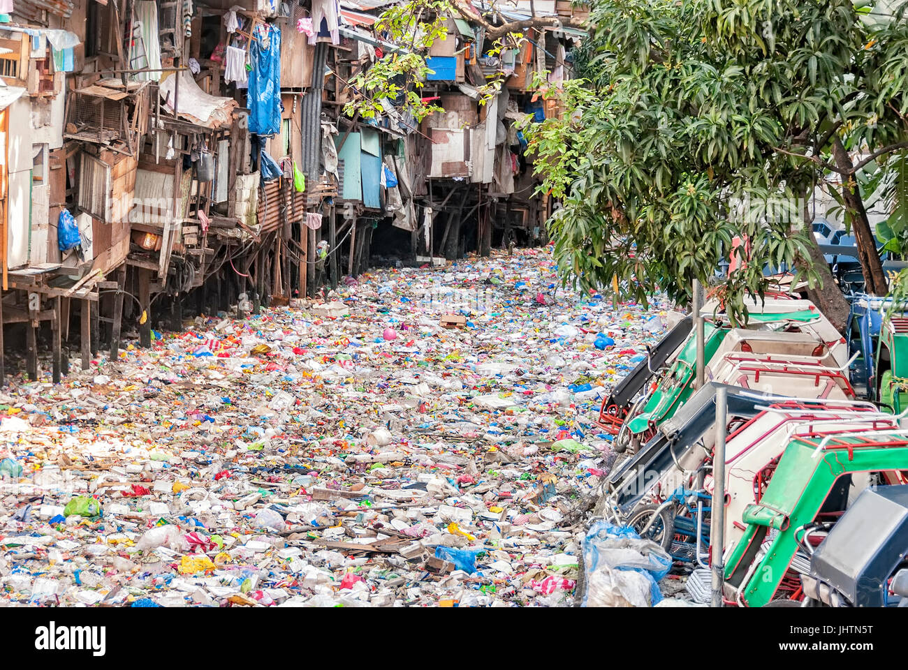 Shanties on stilts standing on garbage-filled river Stock Photo