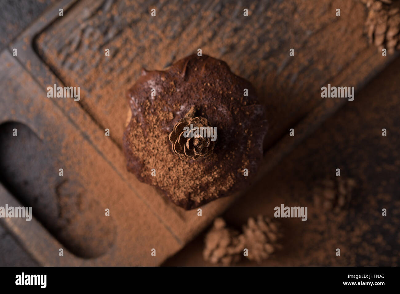 Chocolate muffins, decorated with a small cone on a dark wooden background. Low key. Cupcakes are poured with dark chocolate and cocoa powder. Cupcake Stock Photo