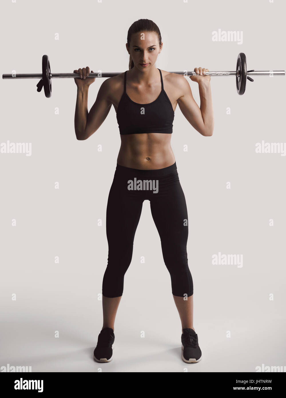 Shot of a beautiful young woman in a workout gear lifting weights Stock