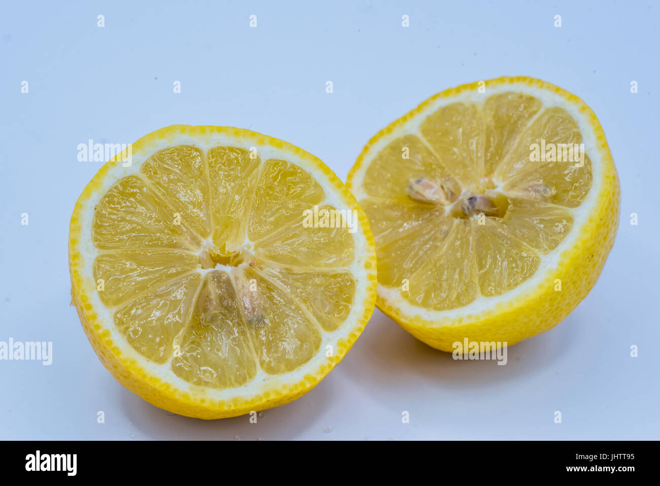 Halved cut juicy fresh yellow lemon with exposed pips or seeds over a