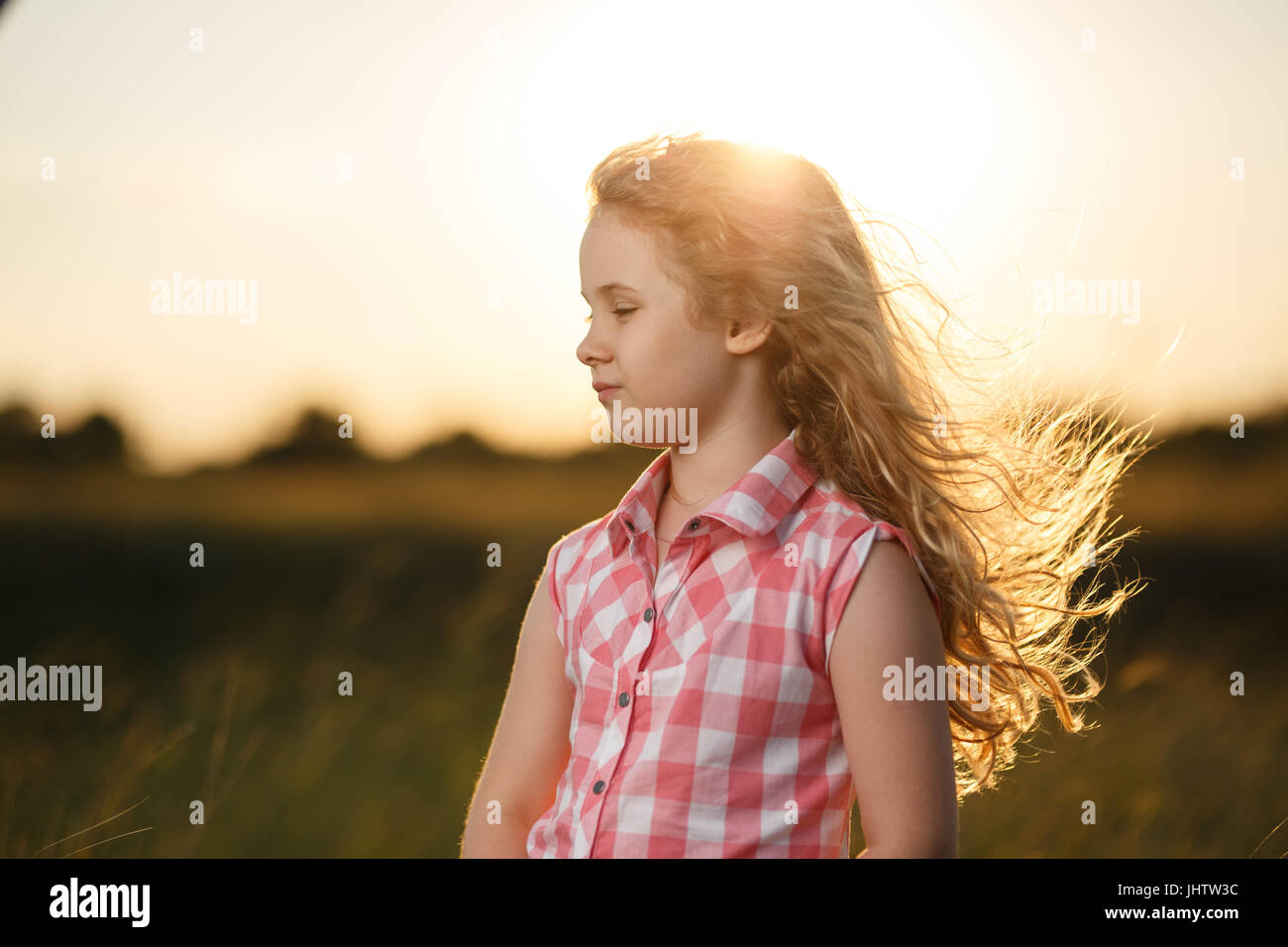 Little blonde child girl standing in summer field at sunset Stock Photo ...
