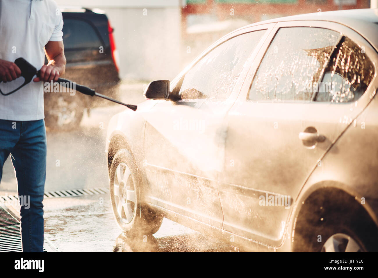 Male worker wash the car with high pressure washer. Car-wash station Stock Photo
