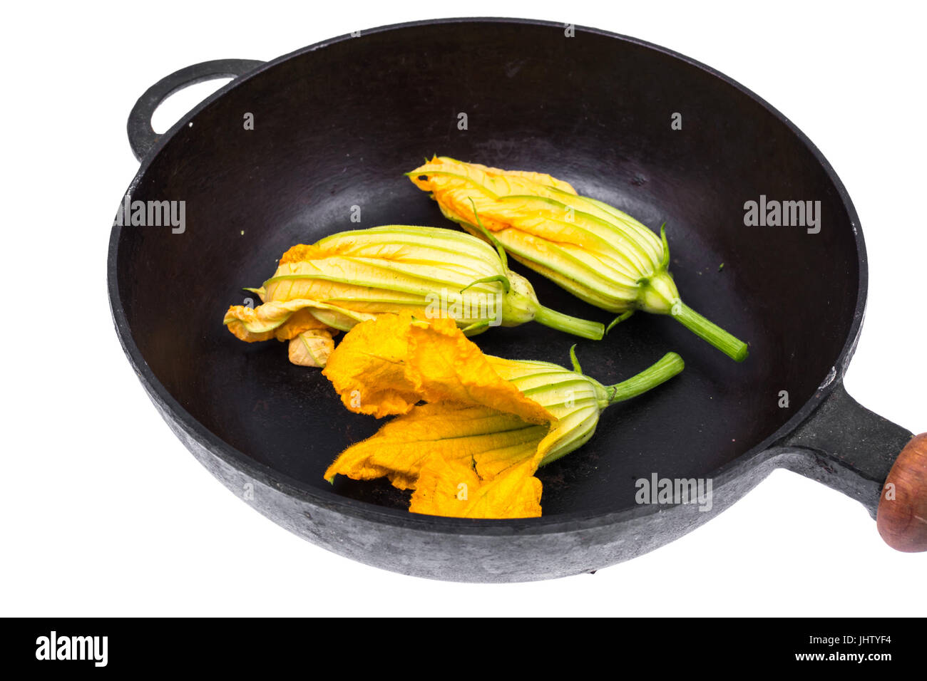 Yellow pumpkin flowers and zucchini in frying pan for cooking. Studio Photo Stock Photo
