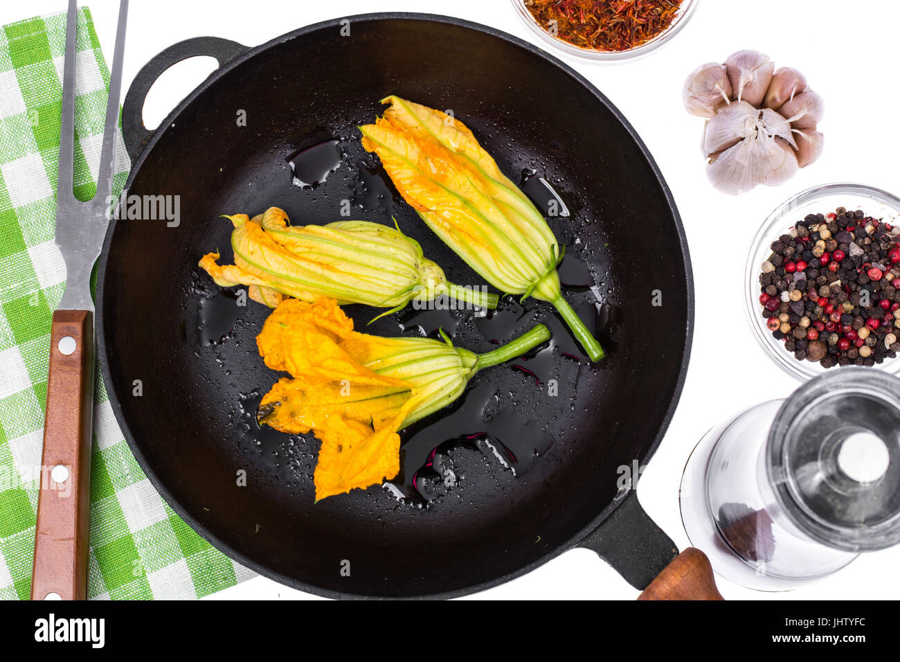 Yellow pumpkin flowers and zucchini in frying pan for cooking. Studio Photo Stock Photo