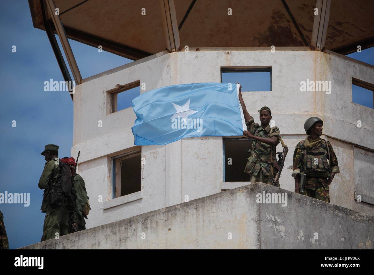 Somalian soldiers and members of the Ras Kimboni militia fly the Somali national flag from the former control tower of the Kismayo Airport while they celebrate its capture from the Al-Qaeda-affiliated extremist group Al Shabaab October 2, 2012 in Kismayo, Somalia.    (photo by Stuart Price  via Planetpix) Stock Photo