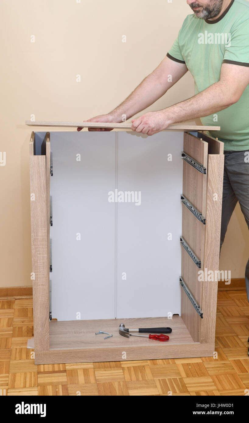 Man Assembling Parts Of New Dresser With Drawer Rails Stock Photo